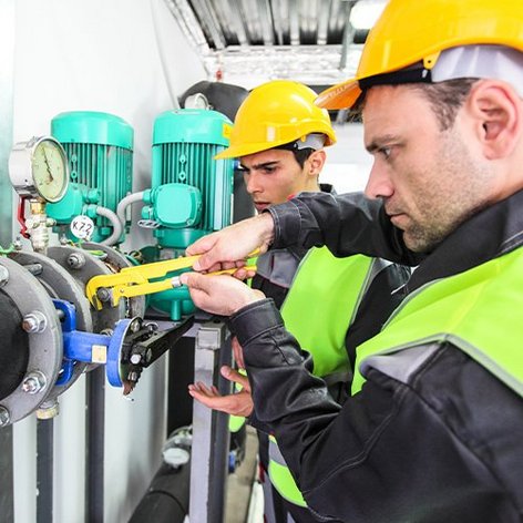 Zwei Monteure die an einem Rohr mit einer Wasserpumpenzange arbeiten