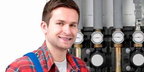 Ein Monteur vor einer Heizungsanlage mit zwei Maulschlüssel in der Hand